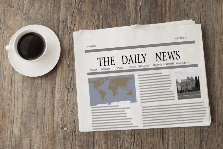 a newspaper and a cup of coffee sit on a light wood surface