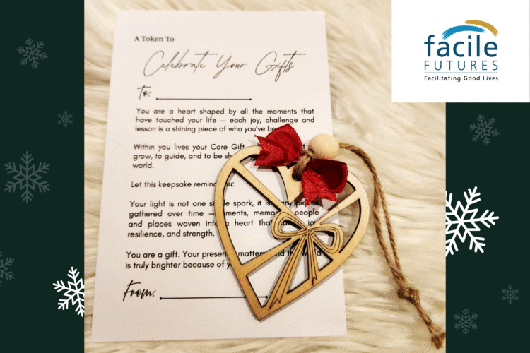 a heart-shaped wooden ornament with a bow lays on top of a white card with text on it. The top of the card reads: Celebrate your Gifts. The rest of the text is partially obscured by the ornament.